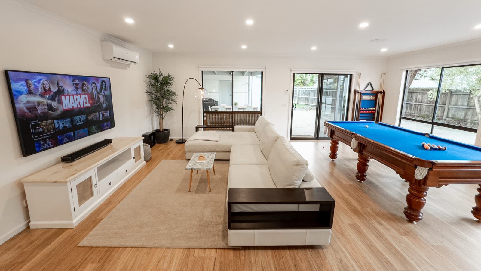 Open plan entertainment room with 75-inch TV, couch and pool table at Big Isle Retreat